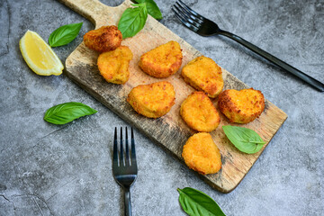 
 Crispy oven baked  chicken nuggets and ketchup. Breaded chicken fillets  with chilly peppers and fresh basi on wooden rustic background