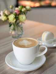 A cup of fresh aromatic cappuccino and macaron on a tableat the cafe. Selective focus.
