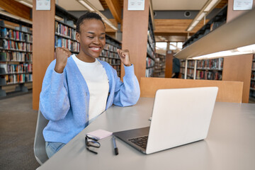 Happy excited African Black girl college student celebrating reading admission email looking at...