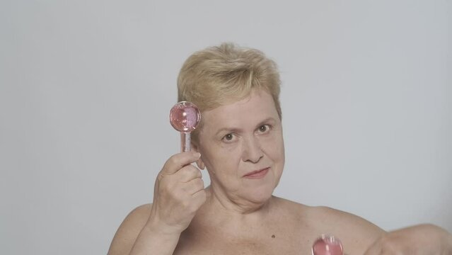 Beautiful blonde woman making a massage with a cooling cryosphere glass globes and looking at the camera. Slow motion HDR BT2020 HLG Material.
