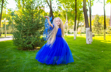 Little girl dressed as a fairy on the background of the park. The concept of a magical holiday....