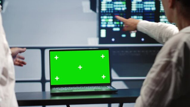Elderly colleagues in server hub housing high end processors capable of quickly and efficiently performing complex computations and data analysis, using chroma key laptop to fix malfunctions