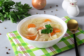 Diet soup with chicken and vermicelli in a white bowl on a light background, Closeup
