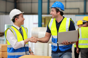 Group of technician engineer in protective uniform with hardhat standing and shaking hands celebrate successful together or completed deal commitment at industry warehouse manufacturing factory