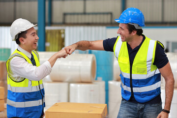 Two technician engineer man in protective uniform with hardhat standing and shaking hands celebrate successful together or completed deal commitment at industry warehouse manufacturing factory