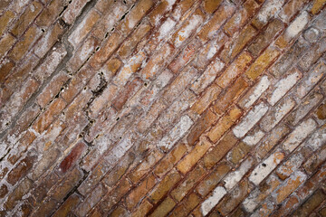 Texture of an antique wall made of bricks in a warm tone and with a diagonal composition.