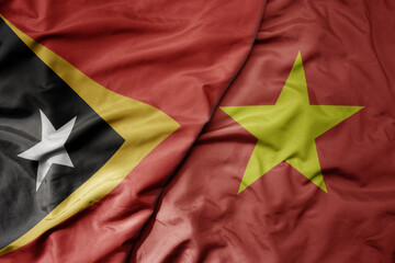 big waving realistic national colorful flag of east timor and national flag of vietnam .