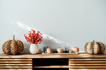Cozy autumn home interior - various decorative wicker pumpkins, candles, seasonal flowers in vase...