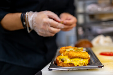 chef hand cooking burger with vegetables and meat on restaurant kitchen
