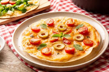 Pizza with tomatoes and cheese in a handmade ceramic plate in front view