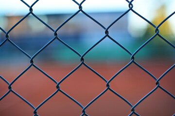 Wire fence mesh pattern. Close up shot, shallow depth of field, dim evening sunset light, no people