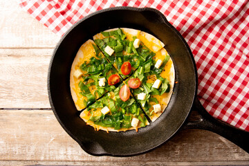 Arugula handmade pizza served in a steel pan board above a wooden table with a red picnic cloth