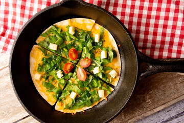 Arugula handmade pizza served in a steel pan board above a wooden table with a red picnic cloth
