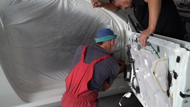 Kyiv, Ukraine - August 12, 2023: Paint shop at the car service station. Paint shop master. Painting a car in a paint booth. Disassembled car after painting