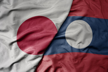 big waving realistic national colorful flag of japan and national flag of laos .