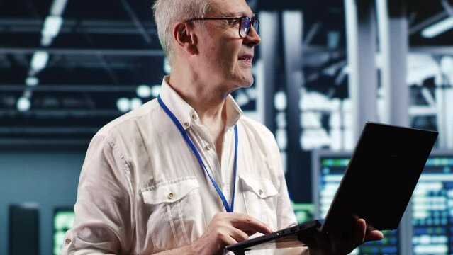Proactive professional navigating network of server hardware in industrial hub. IT consultant with laptop doing optimizations and maintenance in data center, preventing system errors