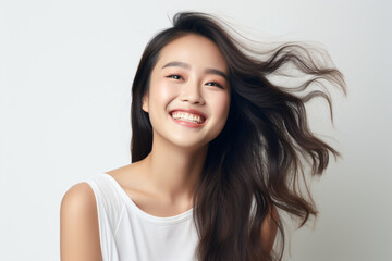 Fototapeta premium A close-up shot of a radiant young Asian woman, smiling with impeccable teeth. Designed for a dental promotion. With a white background. Crafted following the rule of thirds. Generative AI.