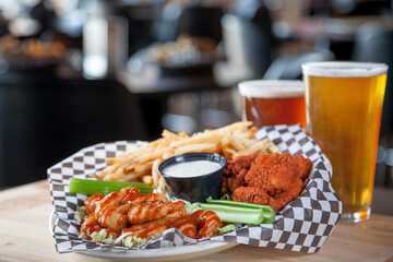 beer and snacks. Tastefully arranged platter of breaded chicken wings, or Buffalo wings, boneless and bone-in wings with fries and tap beer glasses