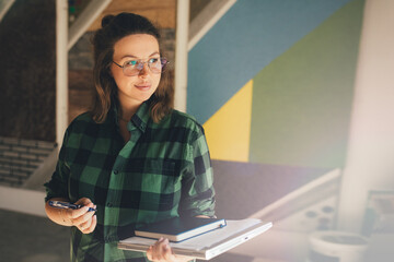 Young woman working in a modern office, making notes in her pad.