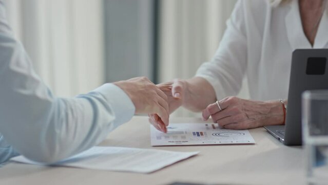 Close up of handshake of business partners agreeing on favorable terms of deal while sitting at table at conference