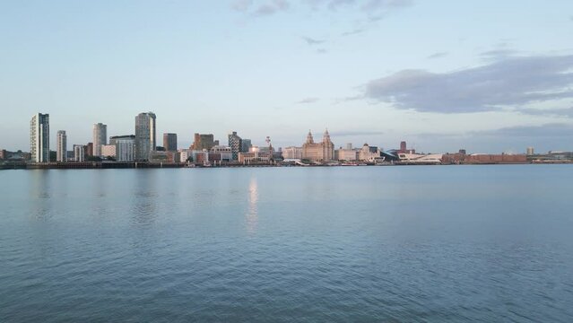Fast aerial approach over water towards Liverpool skyline, Merseyside, England