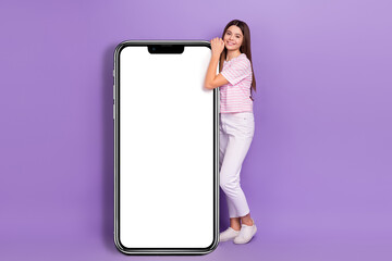 Full size photo of charming schoolgirl showing huge empty space telephone isolated on violet color background