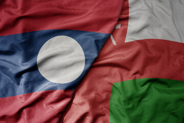 big waving realistic national colorful flag of laos and national flag of oman .