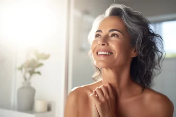 Photo sur Plexiglas Spa Headshot of gorgeous mid age adult 50 years old Latin woman standing in bathroom after shower touching face, looking at reflection in mirror doing morning beauty routine. Older skin care concept.