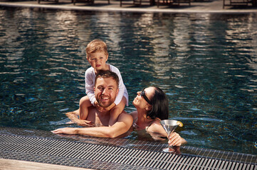 In the water. Happy family of father, mother and son are in the pool