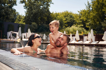 Having fun. Happy family of father, mother and son are in the pool