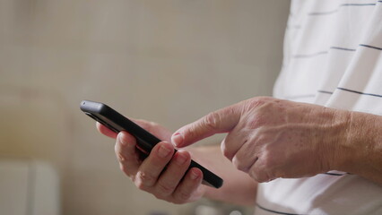 Close-up senior man hands holding cellphone device gesturing. Older person hand and finger pointing at screen, elderly individual using modern technology