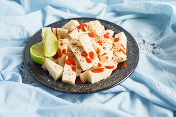 Mexican Traditional snack, jicama or yam bean, with chili, chamoy, sauce and lime