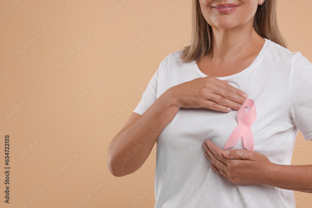 Poster Breast cancer awareness. Woman with pink ribbon doing self-examination on light brown background, closeup. Space for text