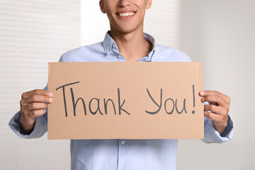 Man holding cardboard sheet with phrase Thank You indoors, closeup