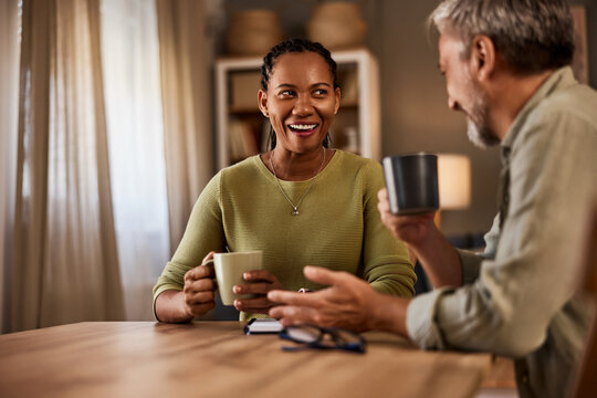 A mature couple at home is engaging in gossip while drinking tea or coffee.