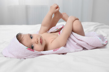 Obraz premium Cute little baby in hooded towel after bathing on bed at home