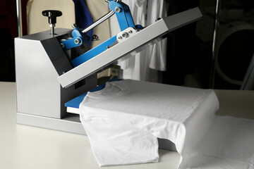 Printing logo. Heat press with t-shirt on white table