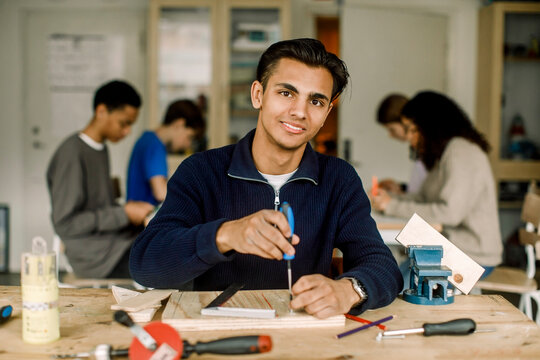 Portrait of smiling male teenage student with screwdriver during carpentry class