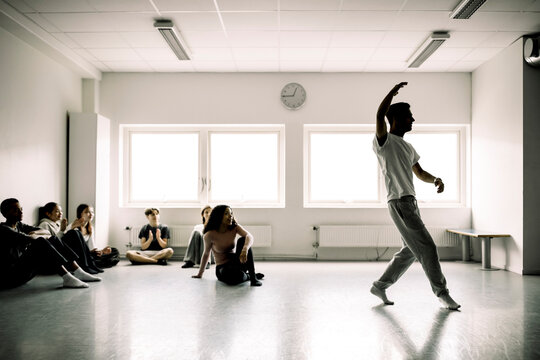 Male and female students looking at boy dancing in studio at high school - Powered by Adobe