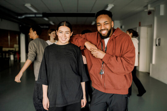 Portrait of smiling male and female teacher standing in dance studio at high school - Powered by Adobe