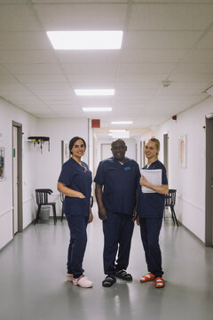 Smiling male doctor standing with female colleagues at healthcare center