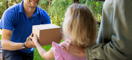 courier service. mother with child accepting home delivery package from smiling delivery man at...