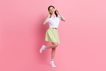 Full length photo of positive carefree young lady wear white shirt listening music dancing isolated pink color background