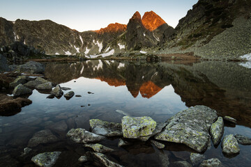 Lake in the mounstains with peaks in background luminated by sunrise