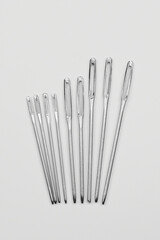Set of silver sewing needles of different sizes isolated on white background top view, flat lay