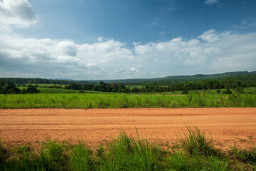 Side view of gravel road in countryside with meadow.