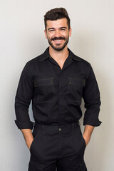 Handsome man posing with hands in pockets and smiling on grey background