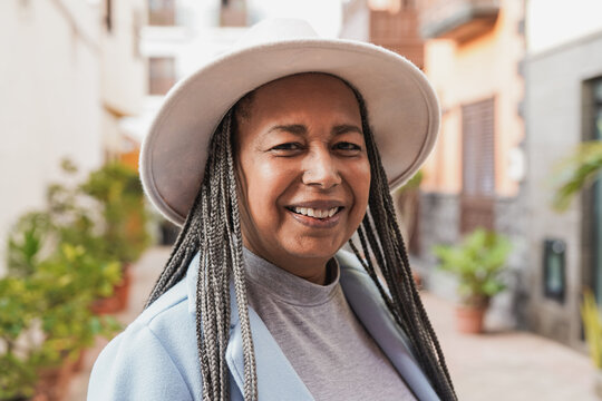 Portrait of happy african senior woman smiling on camera with city in the background during winter time
