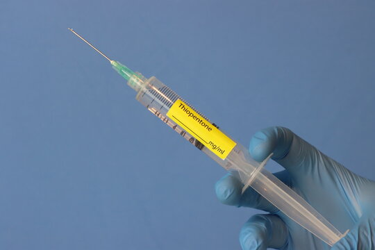 Professional wearing gloves holding thiopentone syringe with copy space in the left