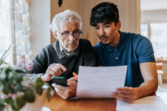 Male care assistant explaining medical reports to senior man at home